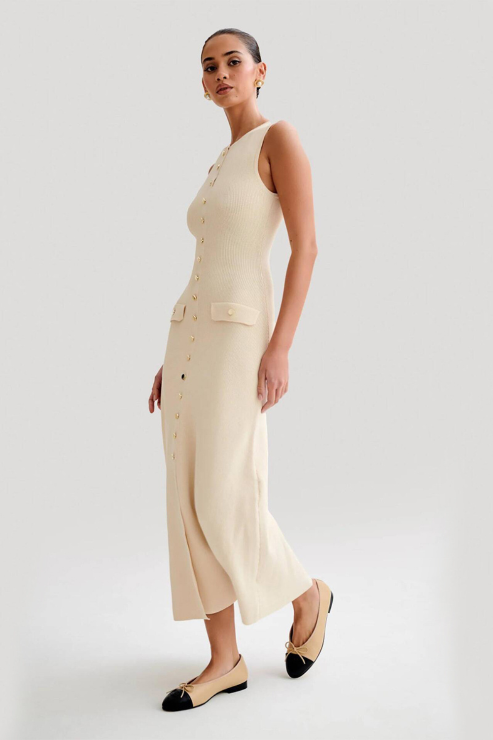 Femme portant une robe longue sans manches couleur abricot, à encolure ronde et boutons décoratifs sur le devant, style élégant et décontracté.