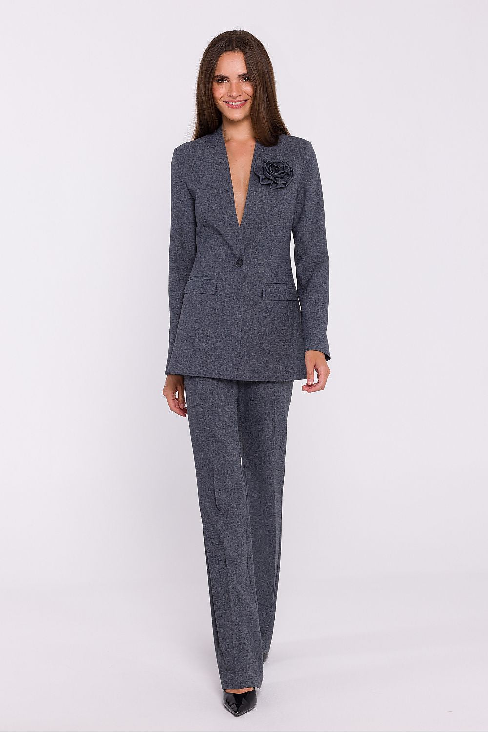 Femme portant un blazer élégant couleur gris avec fleur décorative, fabriqué en Europe, inspiré par la mode parisienne