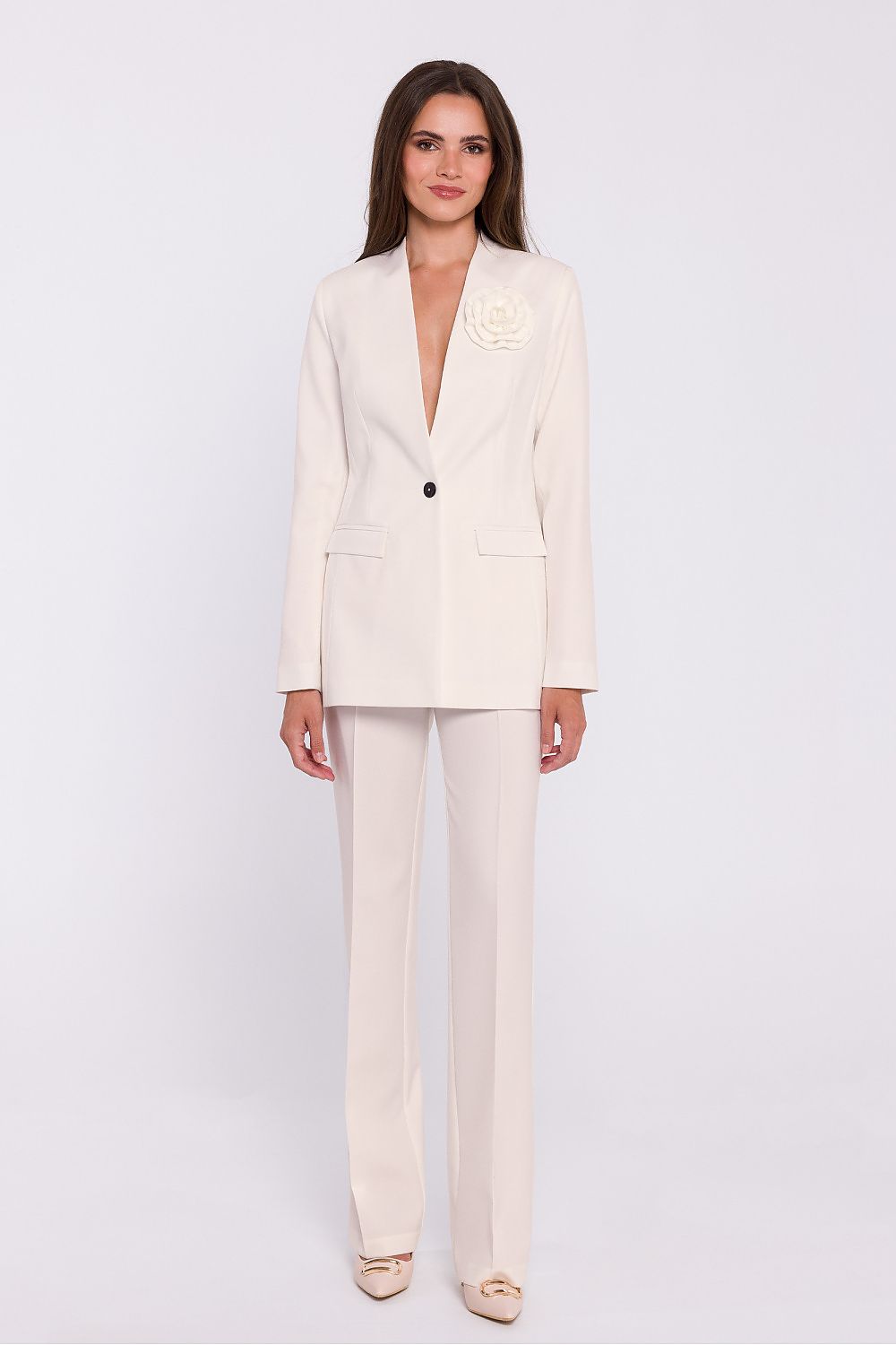 Femme portant un blazer élégant couleur blanc avec fleur décorative, fabriqué en Europe, inspiré par la mode parisienne