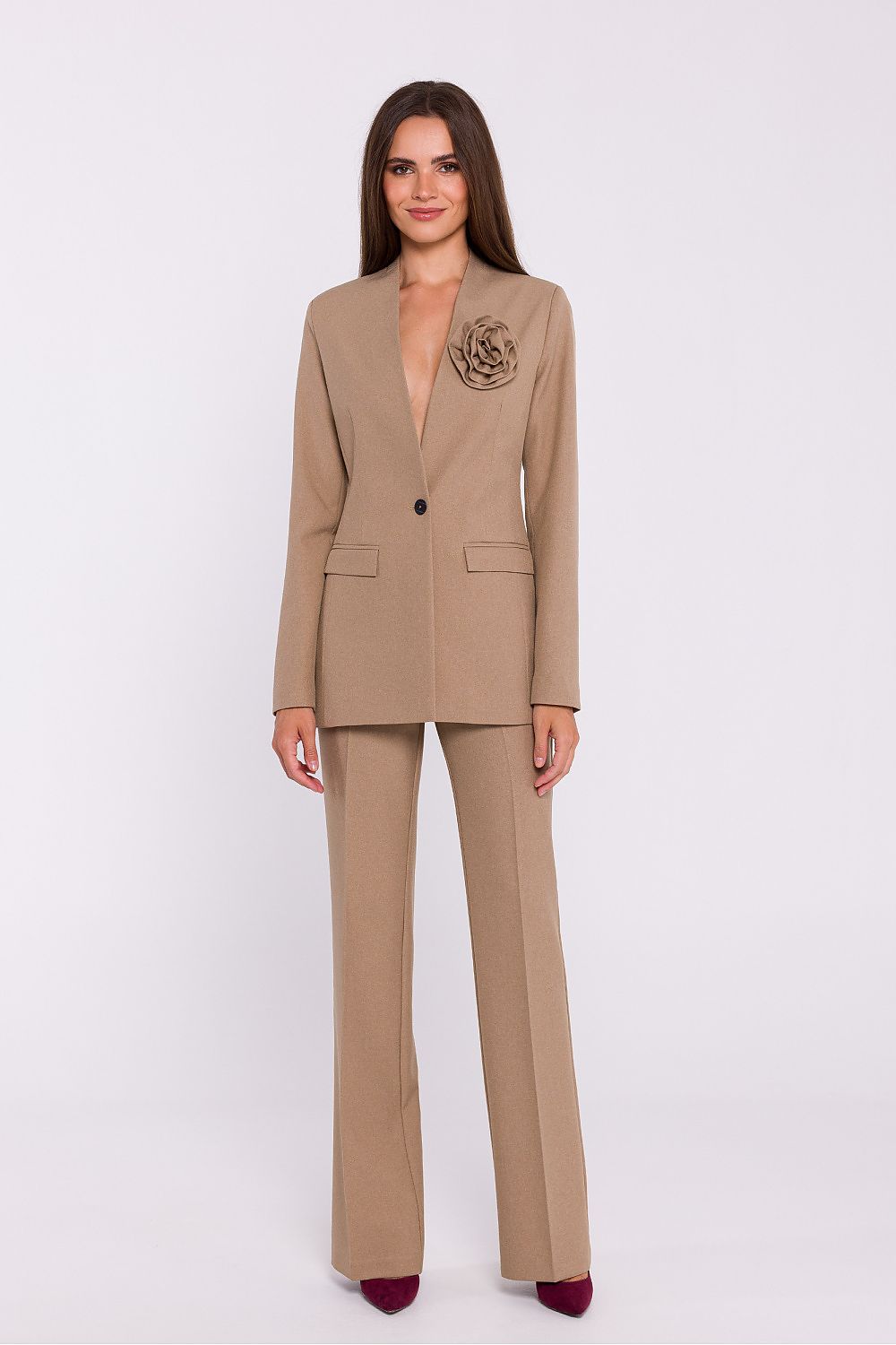 Femme portant un blazer élégant couleur beige avec fleur décorative, fabriqué en Europe, inspiré par la mode parisienne