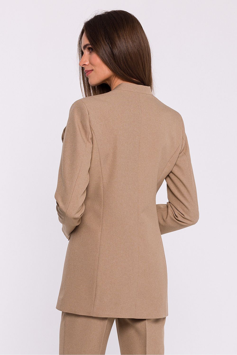 Femme portant un blazer élégant couleur beige avec fleur décorative, fabriqué en Europe, inspiré par la mode parisienne