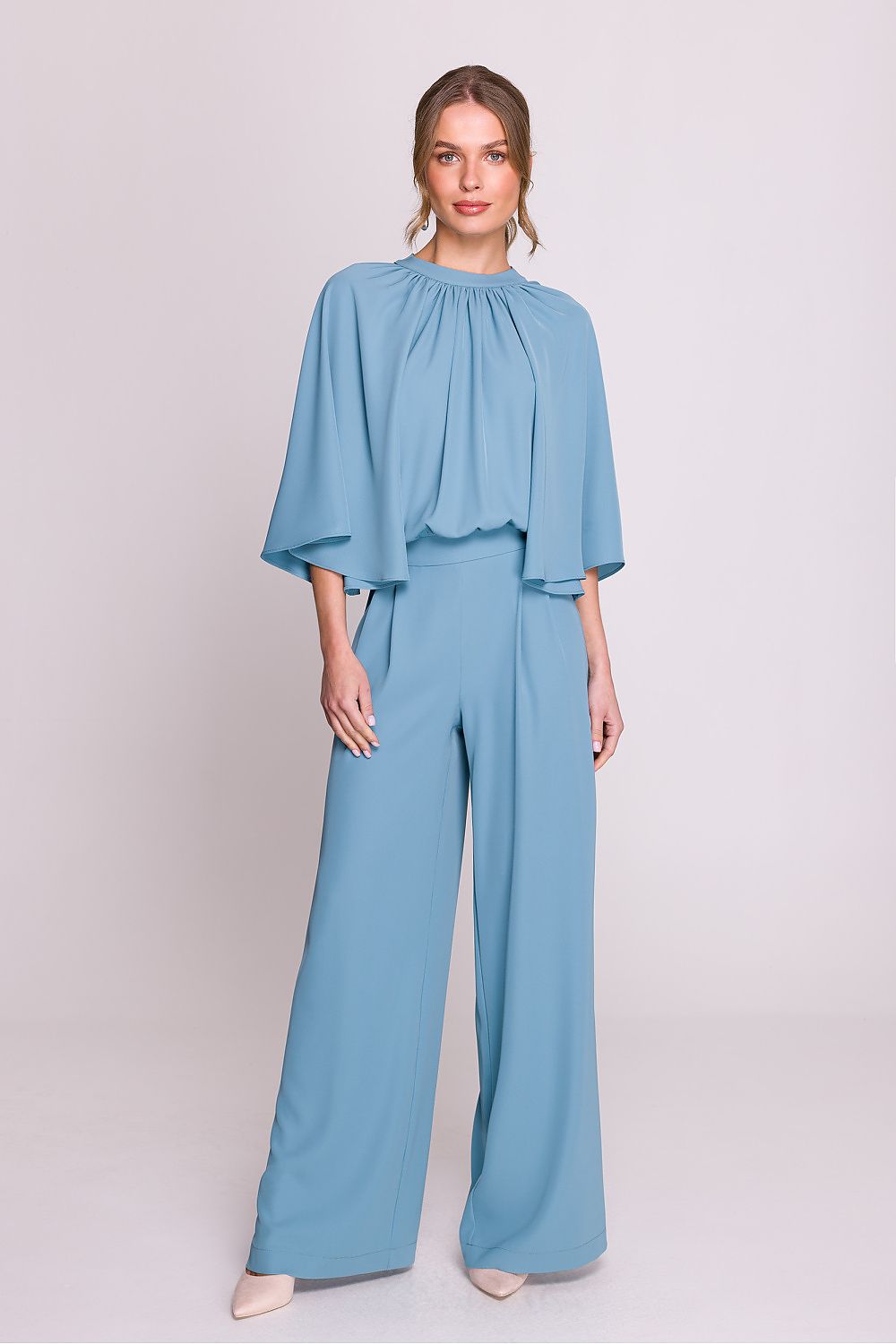 Femme portant un ensemble fluide bleu ciel à manches chauve-souris, pantalon large taille haute, fabriqué en Europe, mode parisienne chic.