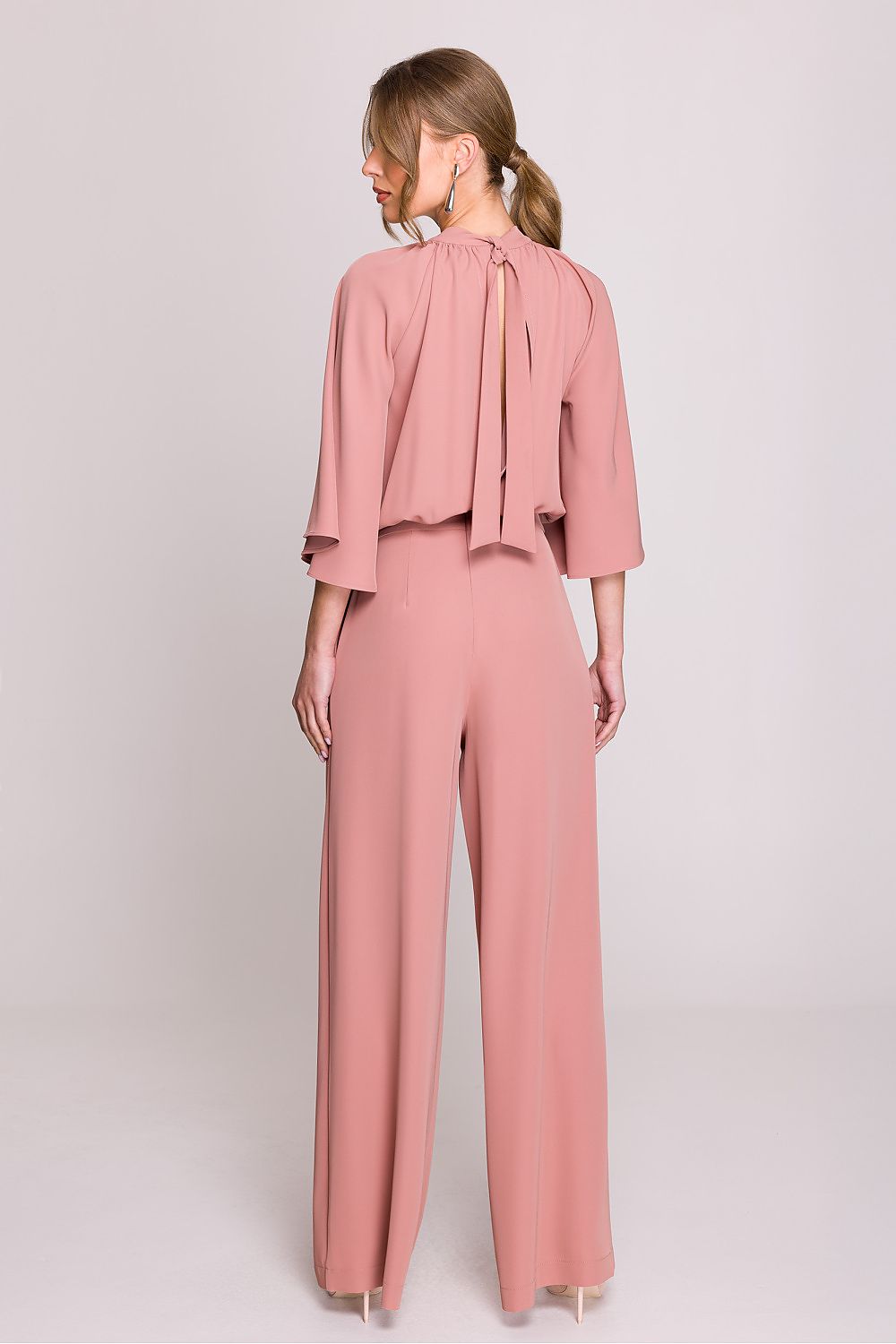 Femme portant un ensemble fluide rose poudré à manches chauve-souris, pantalon large taille haute, fabriqué en Europe, mode parisienne élégante