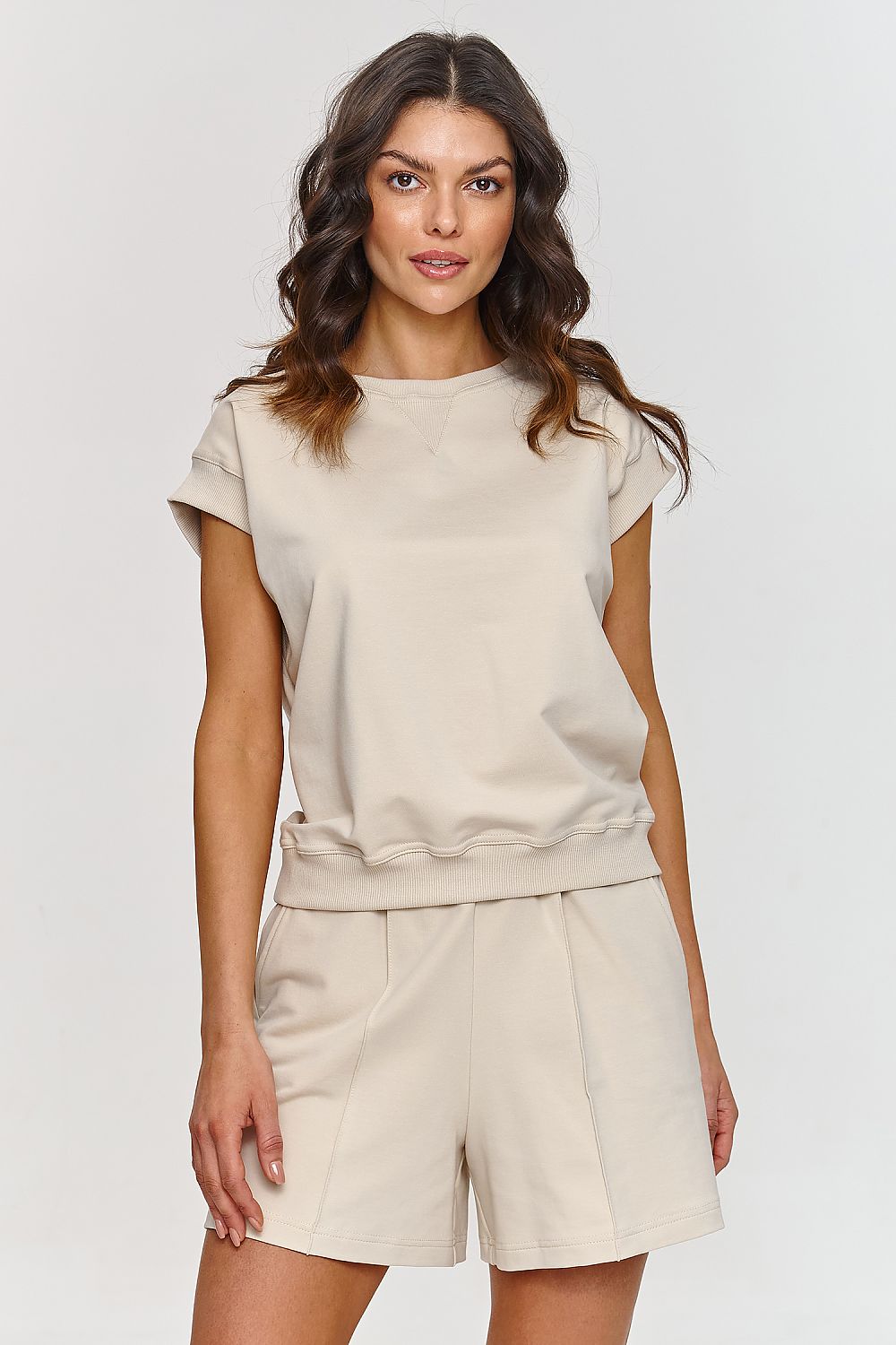 Femme portant un ensemble beige composé d’un haut sans manches et d’un short confortable, style mode parisienne, fabriqué en Europe