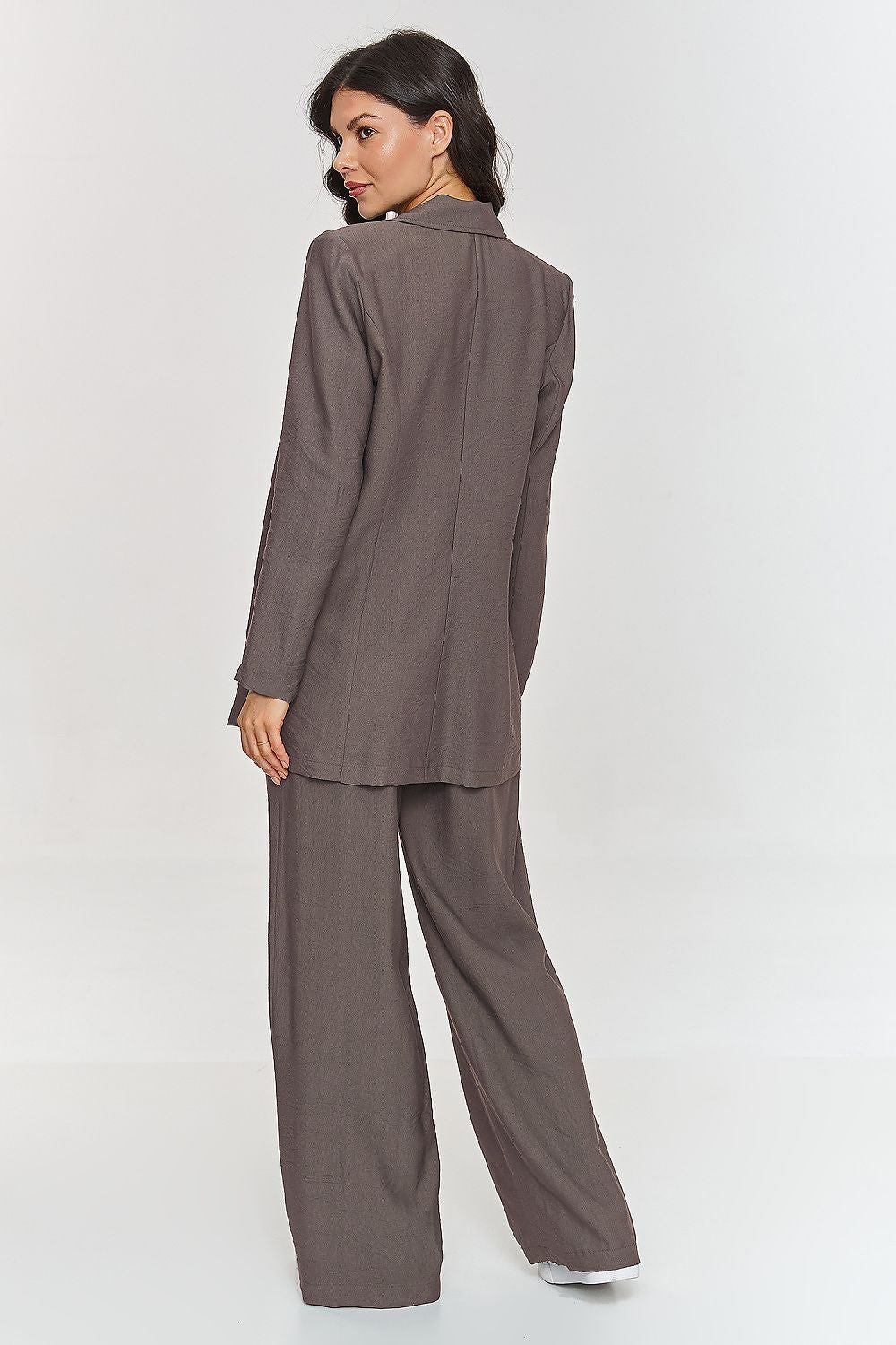 Femme portant un ensemble brun élégant avec blazer ceinturé et pantalon large, fabriqué en Europe, mode parisienne