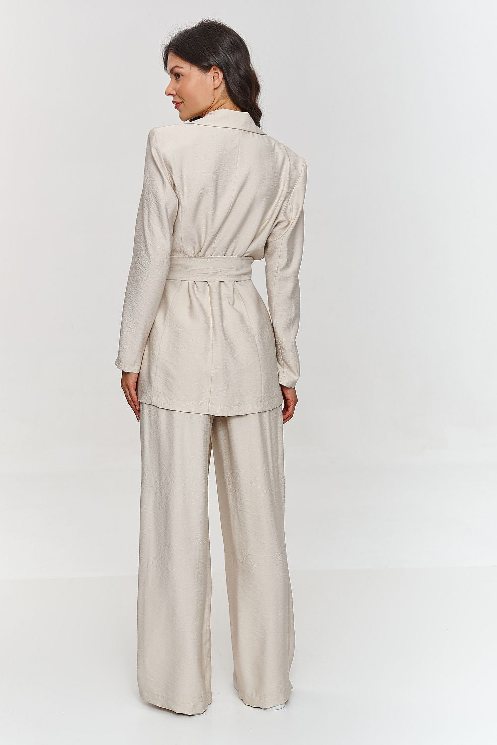 Femme portant un ensemble beige élégant avec blazer ceinturé et pantalon large, fabriqué en Europe, mode parisienne
