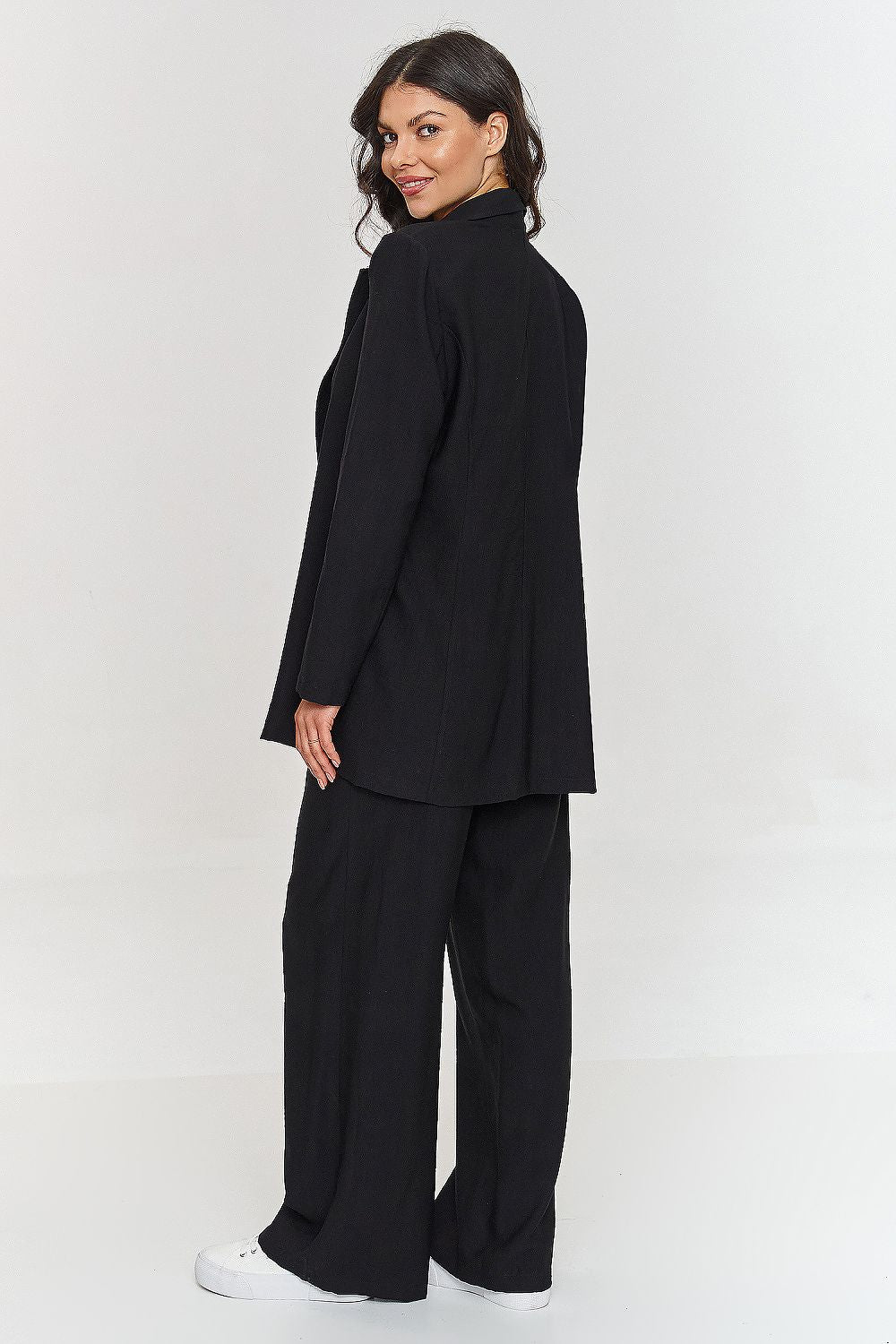 Femme portant un ensemble noir élégant avec blazer ceinturé et pantalon large, fabriqué en Europe, mode parisienne