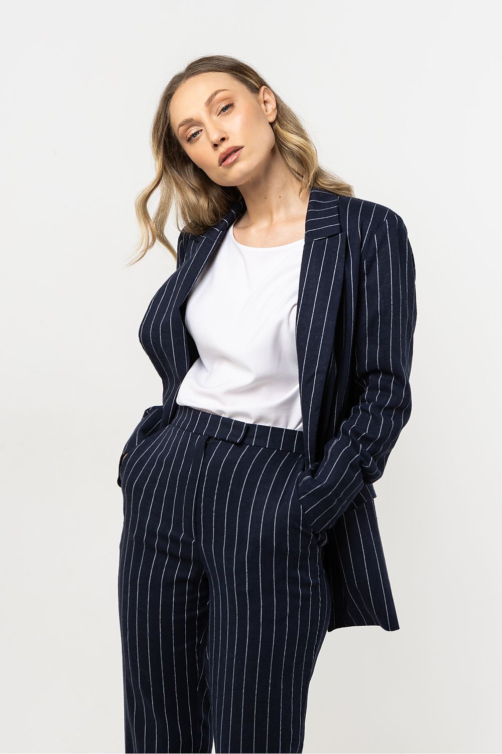 Femme portant une veste en lin bleu marine à rayures délicates, coupe ample et élégante.