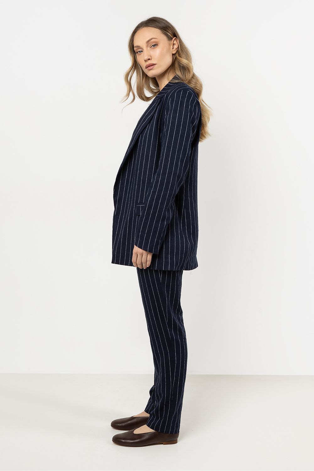 Femme portant une veste en lin bleu marine à rayures délicates, coupe ample et élégante.