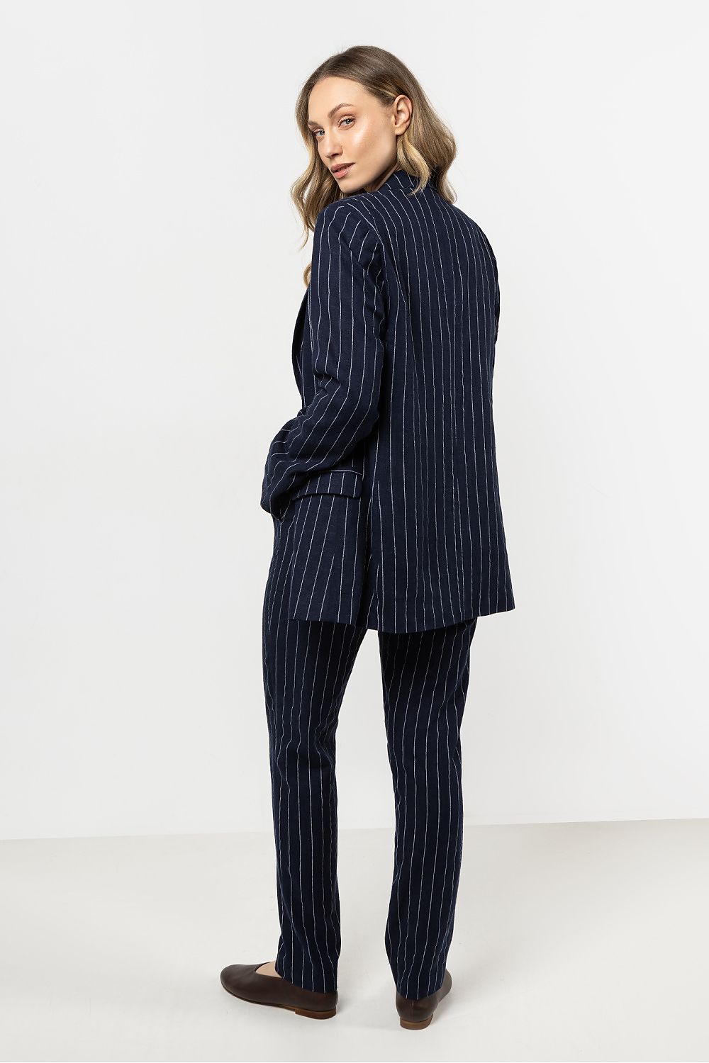 Femme portant une veste en lin bleu marine à rayures délicates, coupe ample et élégante.