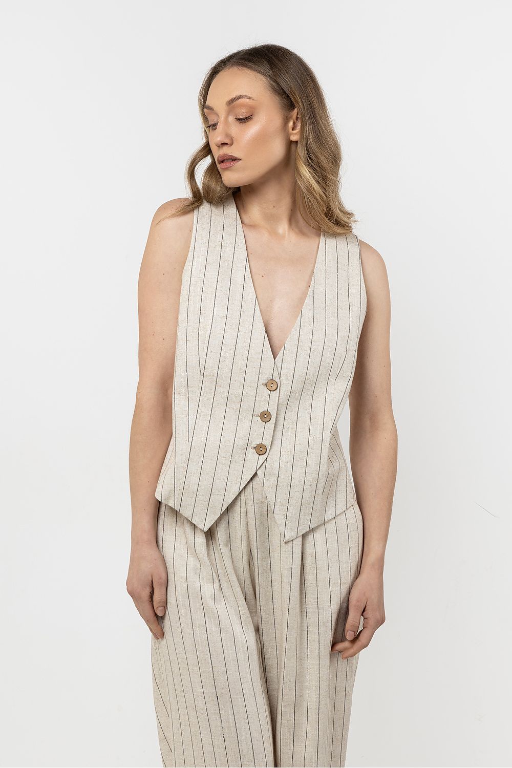 Femme portant un gilet sans manches en lin beige clair à rayures subtiles, style estival chic