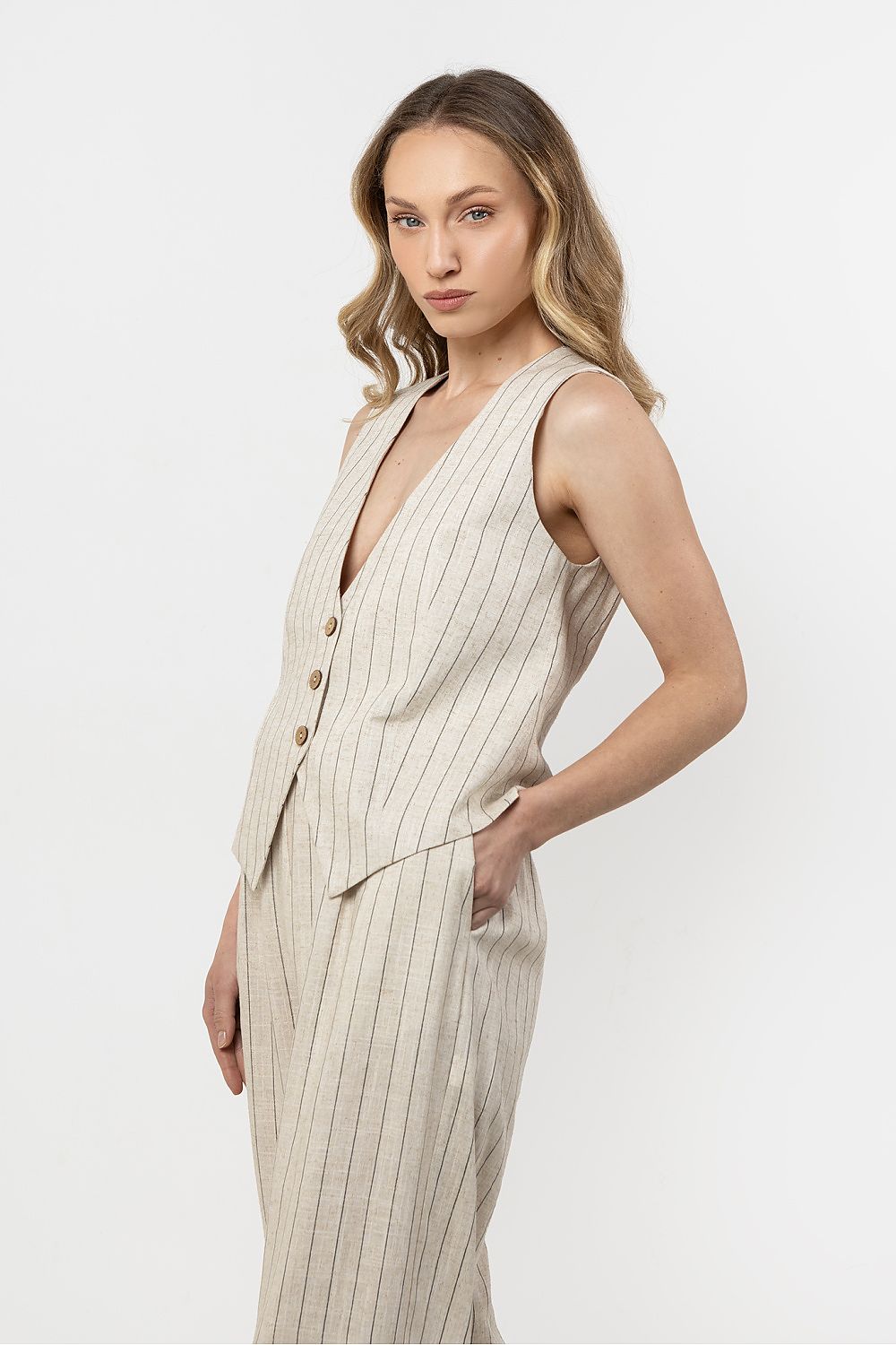 Femme portant un gilet sans manches en lin beige clair à rayures subtiles, style estival chic