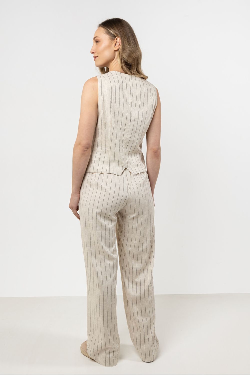 Femme portant un gilet sans manches en lin beige clair à rayures subtiles, style estival chic