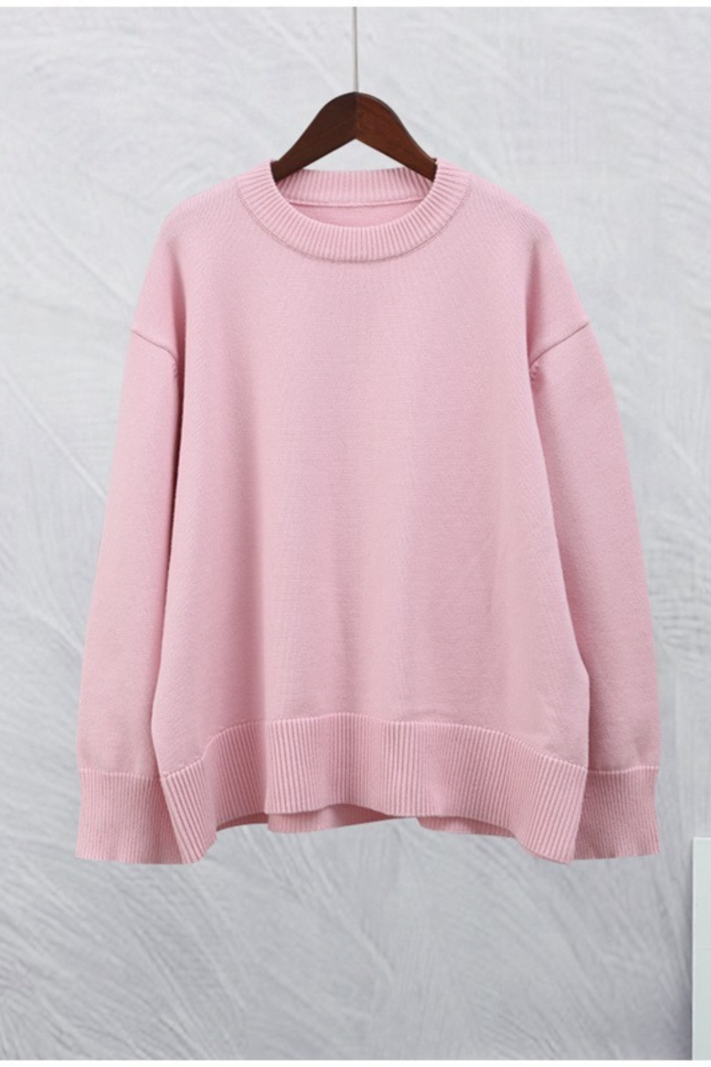 Pull rose pastel à col rond et coupe ample, porté avec un jean clair — idéal pour un look décontracté et doux au quotidien.