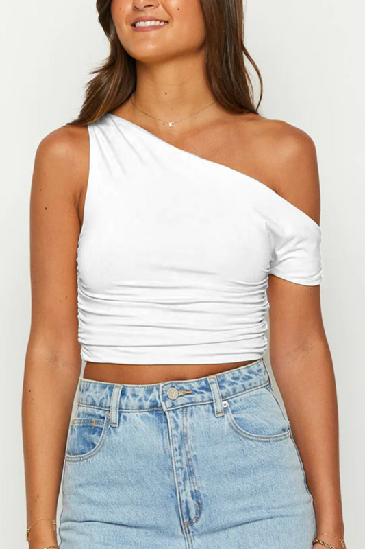 Femme portant un top blanc asymétrique à une seule épaule, ajusté et court, parfait pour un look estival décontracté avec un jean taille haute.
