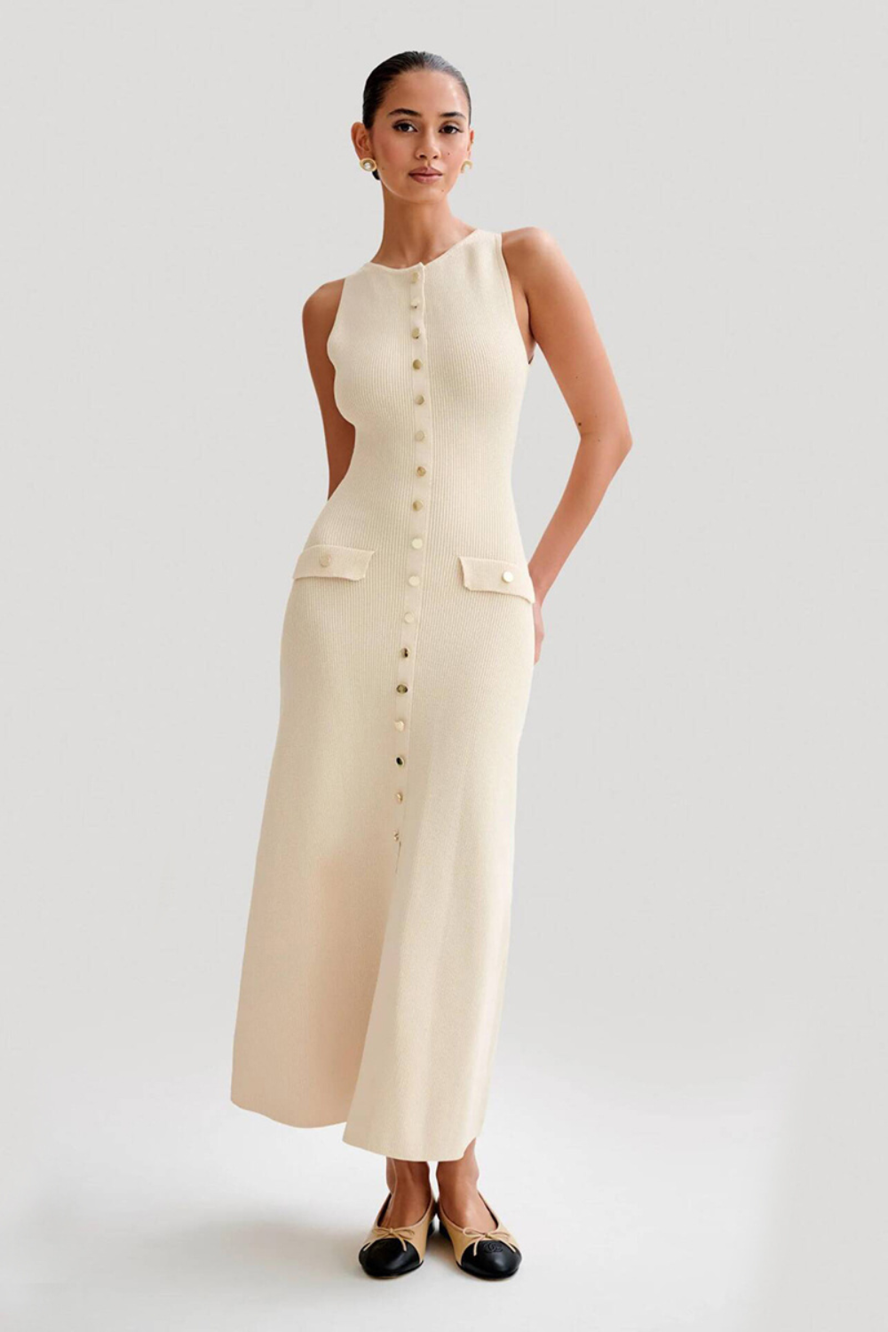 Femme portant une robe longue sans manches couleur abricot, à encolure ronde et boutons décoratifs sur le devant, style élégant et décontracté.