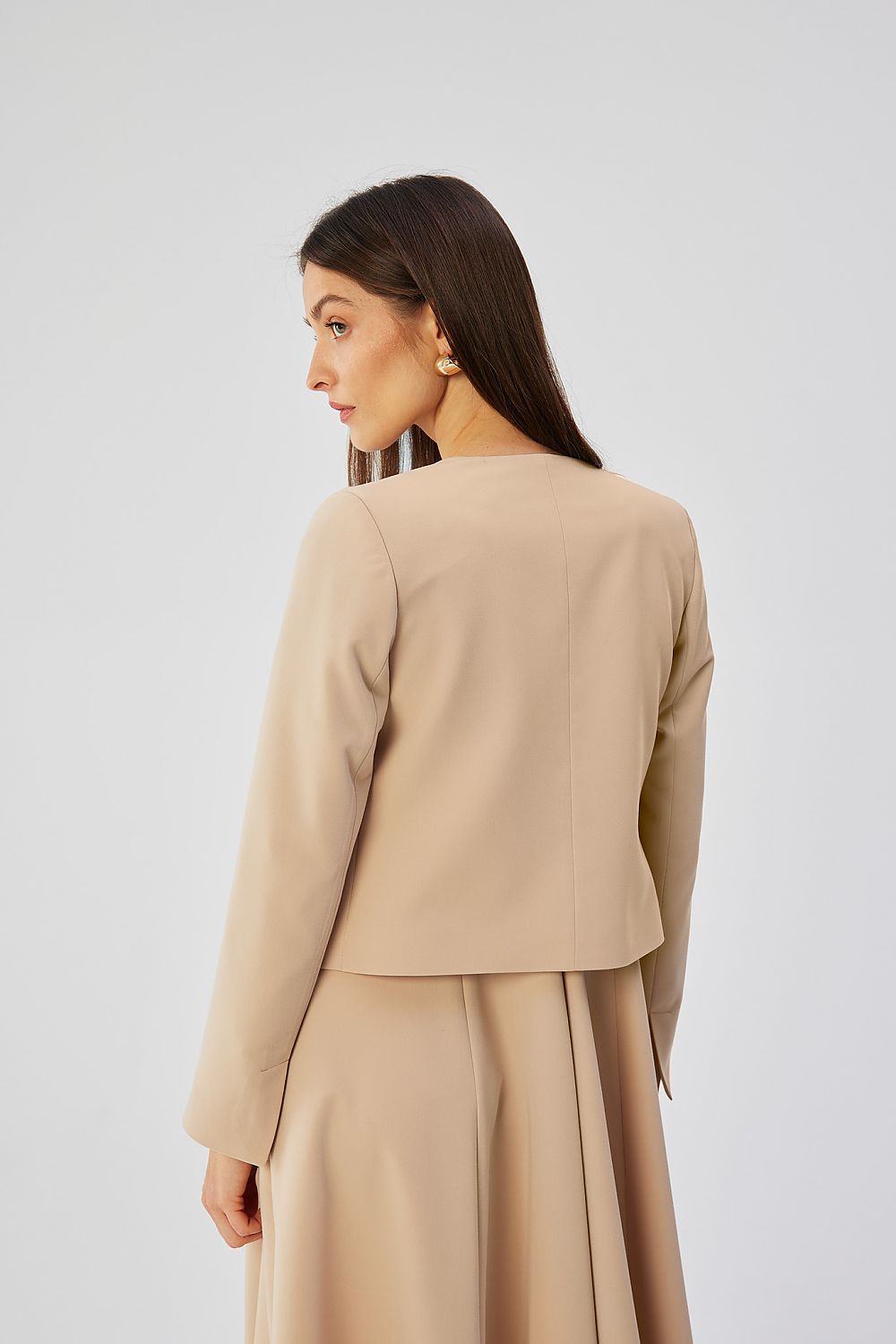 Veste courte beige VidenaParis, style élégant et décontracté, portée avec une robe fluide pour un look moderne.