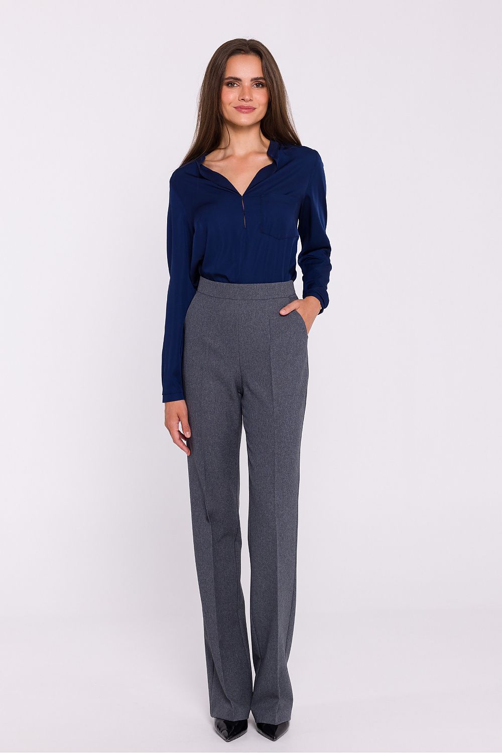 Femme portant une blouse satinée bleu marine à col montant, manches longues et poche poitrine, fabriquée en Europe, mode parisienne