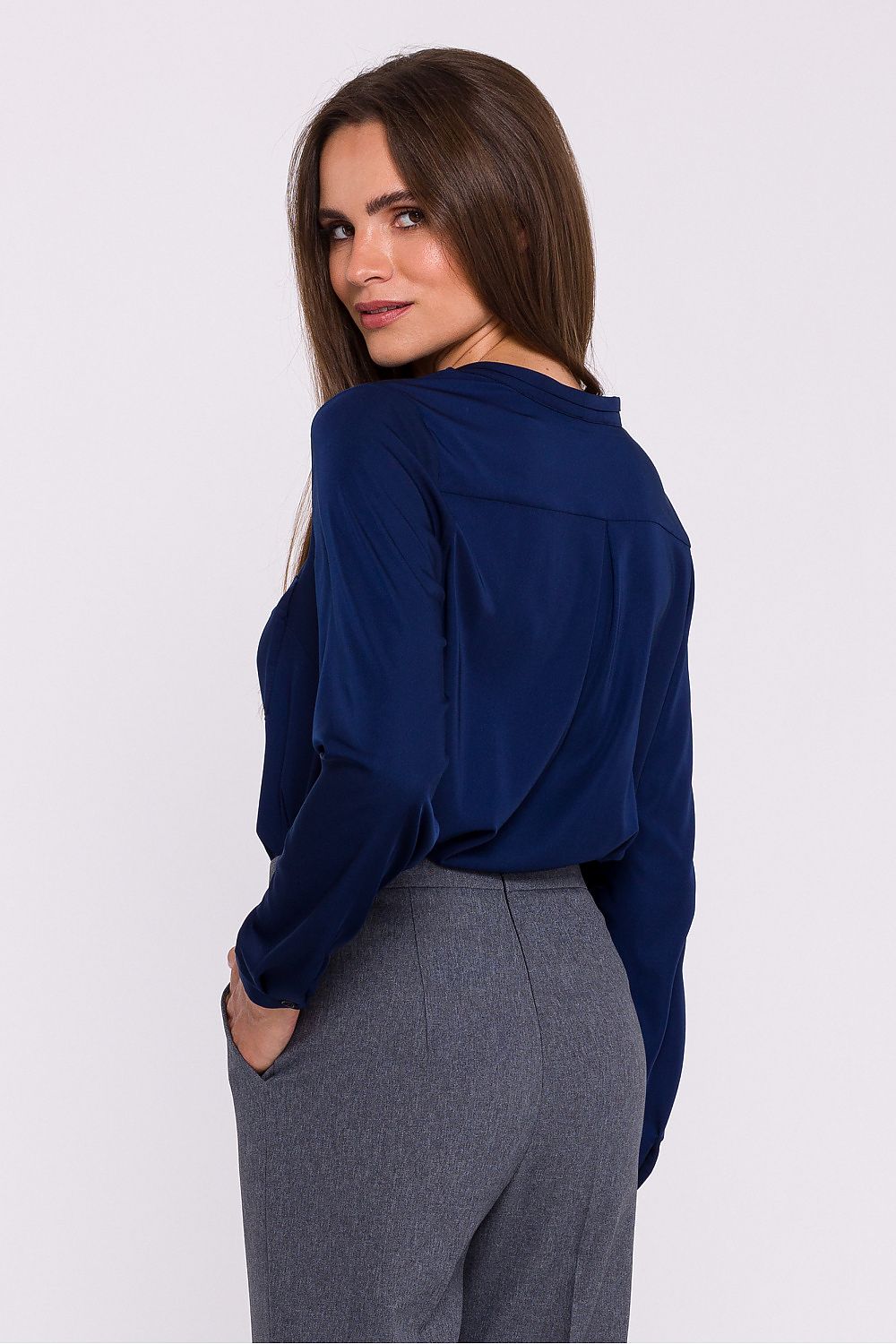 Femme portant une blouse satinée bleu marine à col montant, manches longues et poche poitrine, fabriquée en Europe, mode parisienne