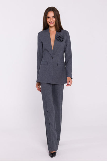 Femme portant un blazer élégant couleur gris avec fleur décorative, fabriqué en Europe, inspiré par la mode parisienne