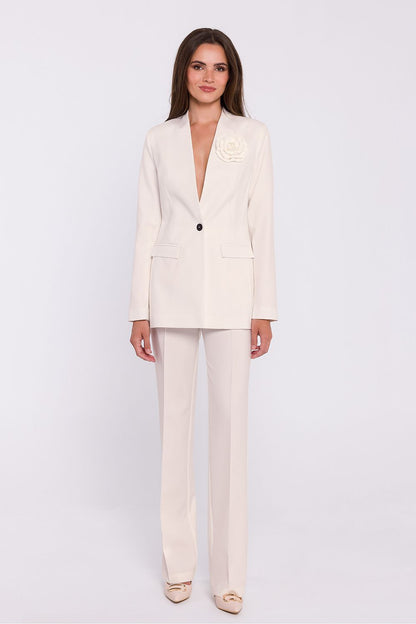 Femme portant un blazer élégant couleur blanc avec fleur décorative, fabriqué en Europe, inspiré par la mode parisienne 
