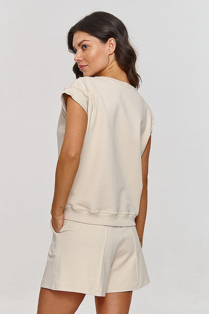 Femme portant un ensemble beige composé d’un haut sans manches et d’un short confortable, style mode parisienne, fabriqué en Europe

