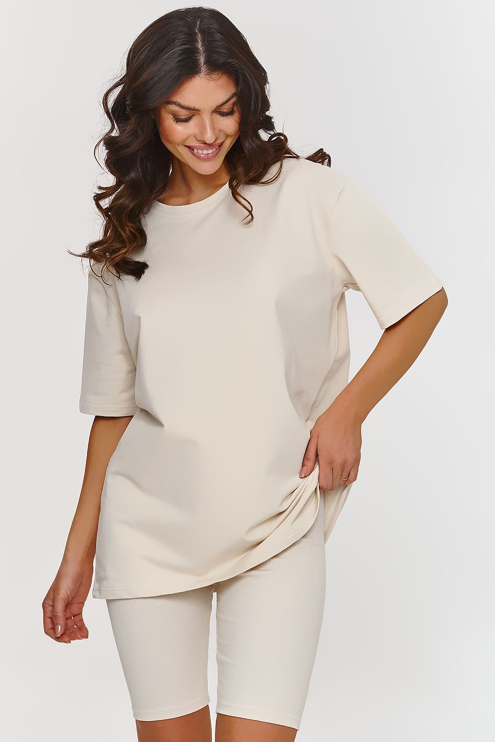 Femme portant un ensemble beige avec t-shirt ample et short legging confortable, inspiré par la mode parisienne, fabriqué en Europe