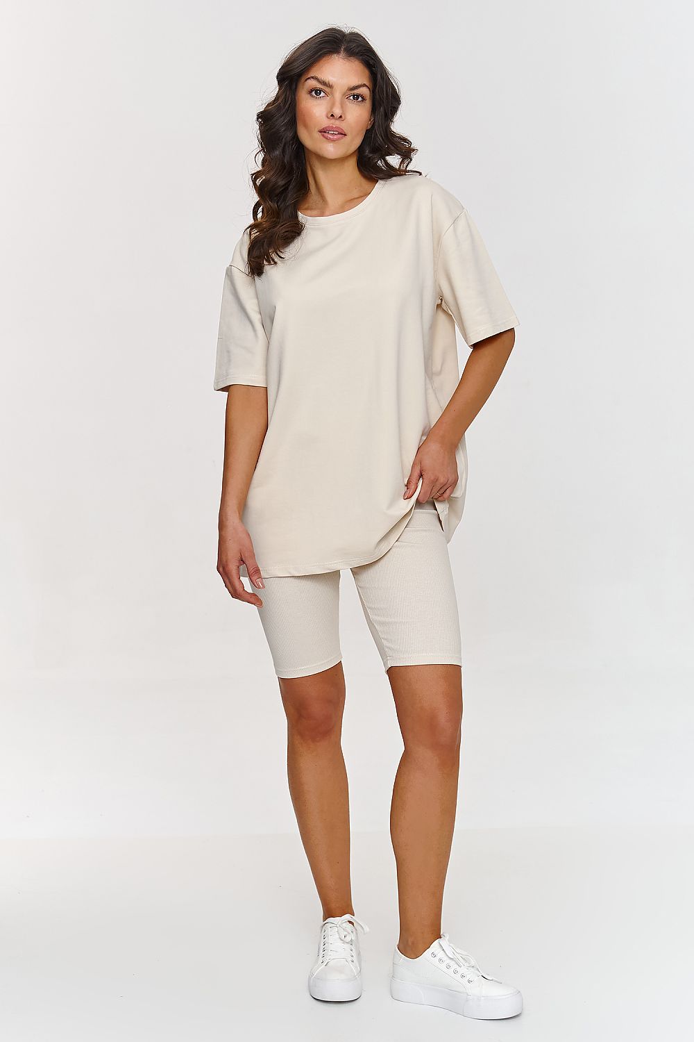 Femme portant un ensemble beige avec t-shirt ample et short legging confortable, inspiré par la mode parisienne, fabriqué en Europe