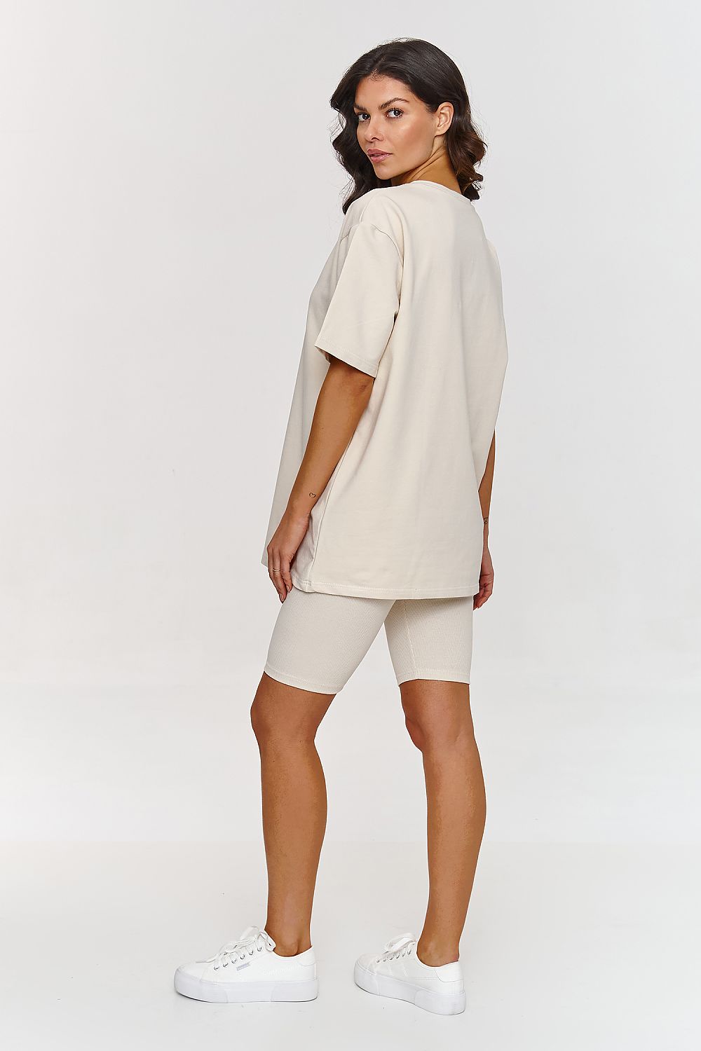 Femme portant un ensemble beige avec t-shirt ample et short legging confortable, inspiré par la mode parisienne, fabriqué en Europe
