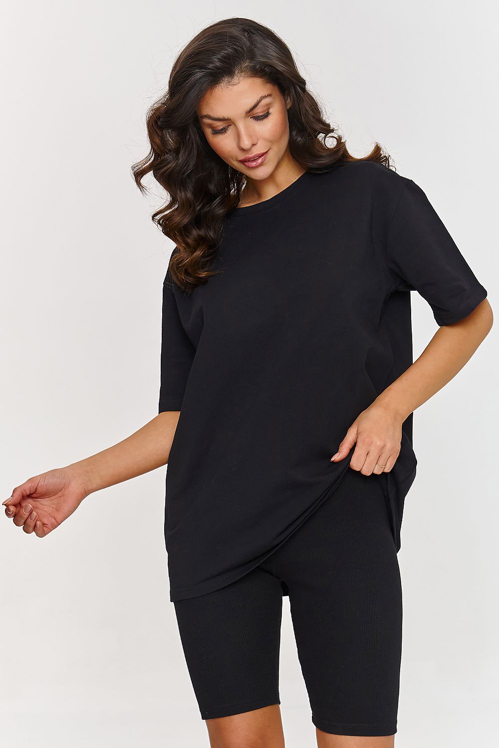Femme portant un ensemble noir composé d’un t-shirt oversize et d’un short legging stretch, mode parisienne, fabriqué en Europe