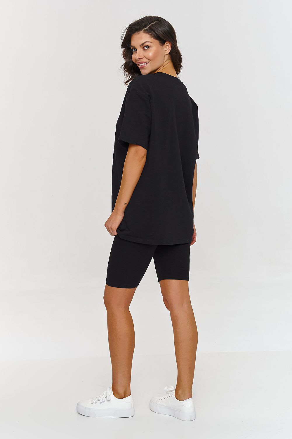 Femme portant un ensemble noir composé d’un t-shirt oversize et d’un short legging stretch, mode parisienne, fabriqué en Europe