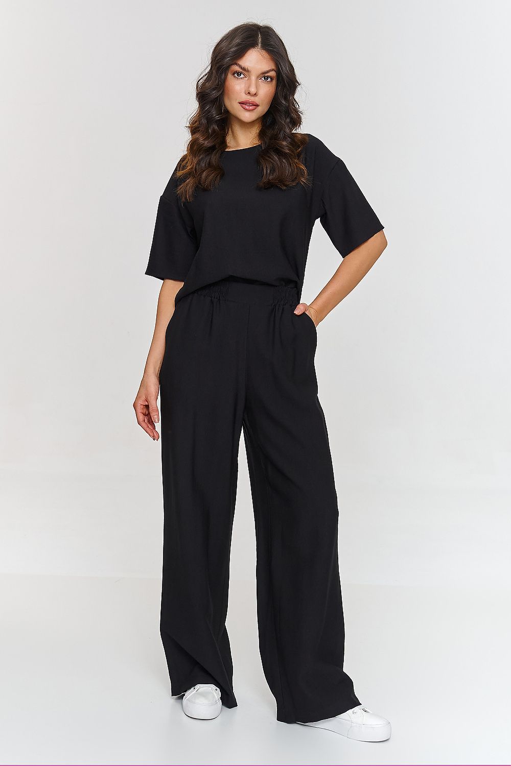 Femme portant un ensemble noir décontracté avec haut à manches courtes et pantalon large, fabriqué en Europe, mode parisienne
