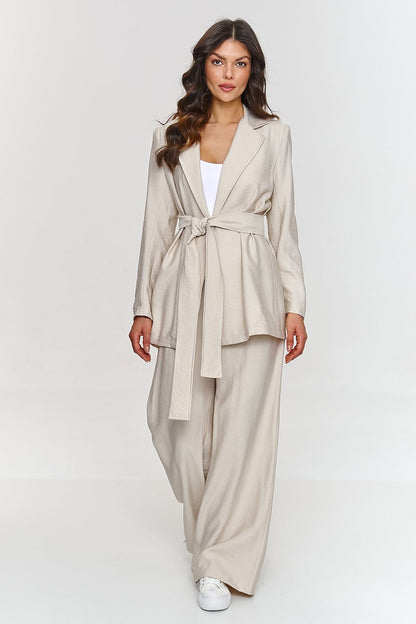 Femme portant un ensemble beige élégant avec blazer ceinturé et pantalon large, fabriqué en Europe, mode parisienne