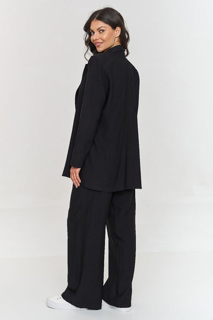 Femme portant un ensemble noir élégant avec blazer ceinturé et pantalon large, fabriqué en Europe, mode parisienne