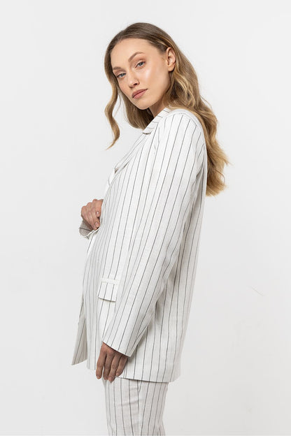  Femme portant une veste en lin blanc à rayures discrètes, coupe fluide et sophistiquée.