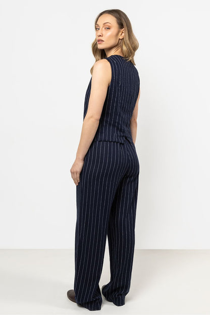 Femme portant un gilet sans manches en lin bleu marine à rayures fines, coupe courte élégante.