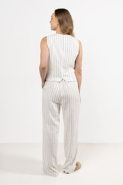 Femme portant un gilet sans manches en lin blanc, coupe droite et col en V sophistiqué.